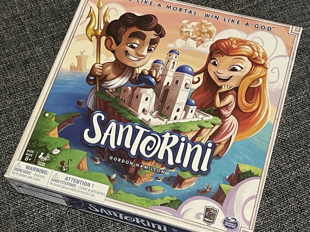 Santorini game box featuring an illustration of two gods looking over an island city of towers